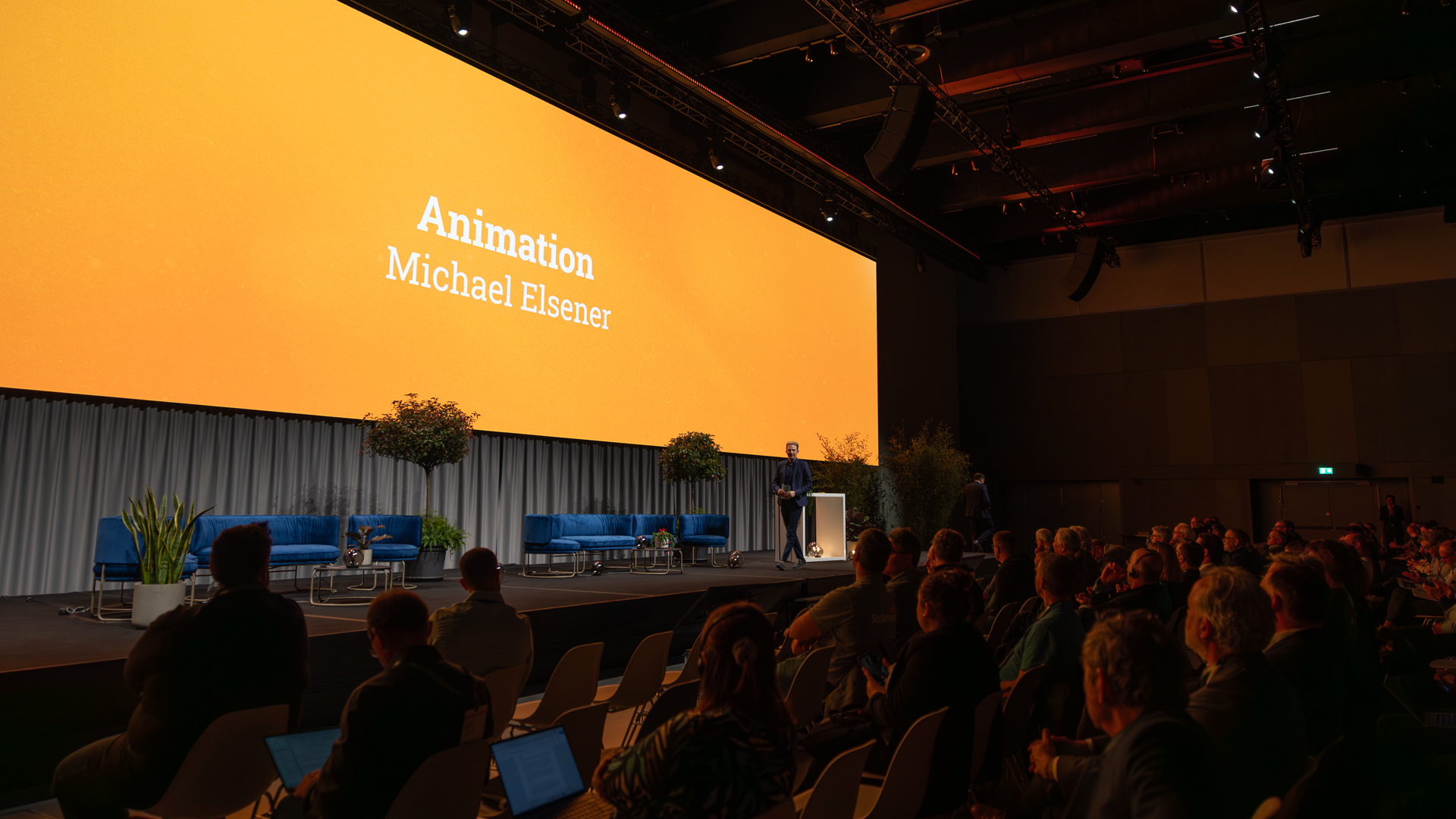 Orangener Screen mit Publikum im Vordergrund | © Swissolar / Sarah Bollmann, atelier olive GmbH