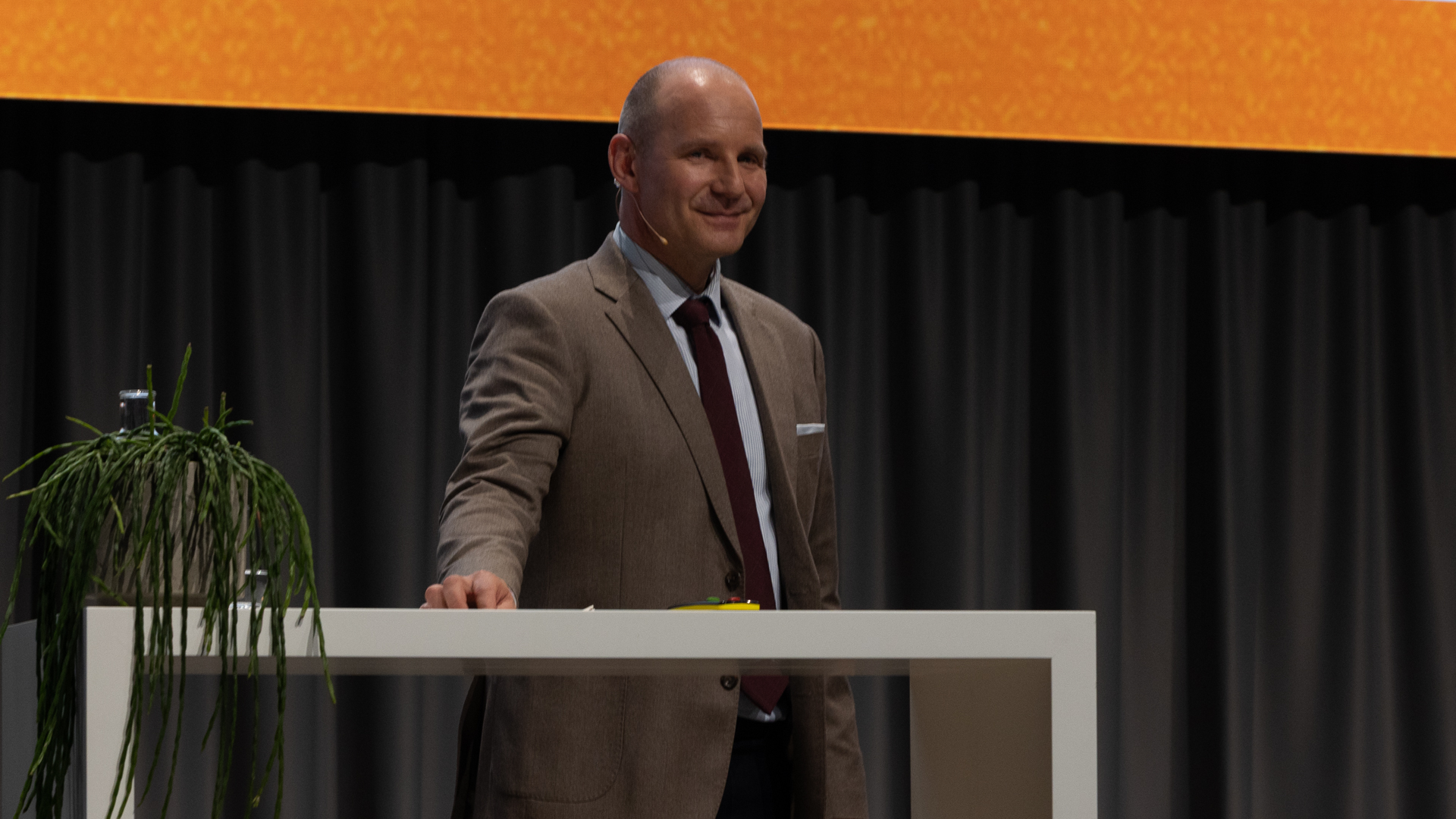 Mann mit braunem Jacket hinter weissen Stehtisch | © Swissolar / Sarah Bollmann